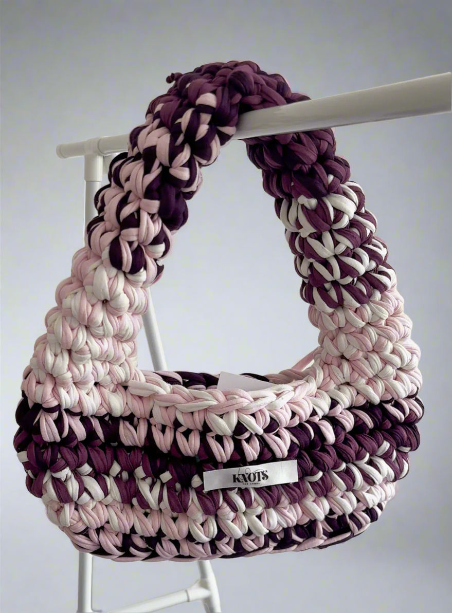 Crocheted handbag with pink, purple, and white pattern on a white background