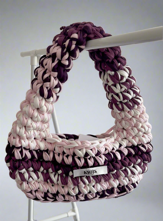 Crocheted handbag with pink, purple, and white pattern on a white background